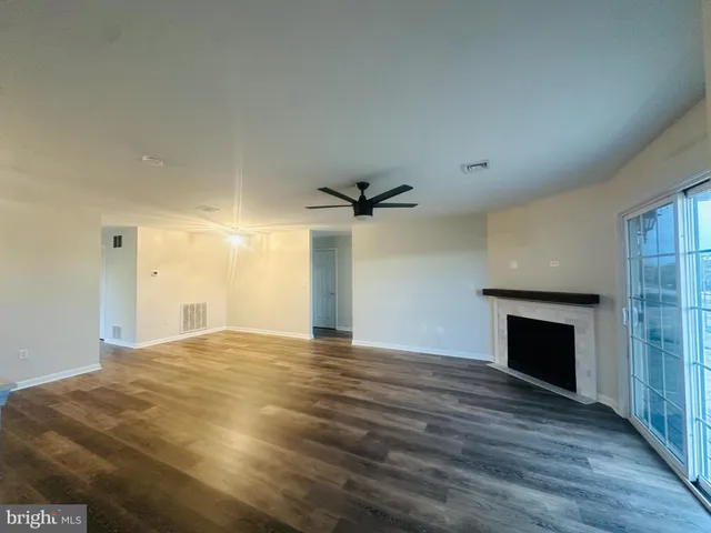 an empty room with wooden floor fireplace and windows