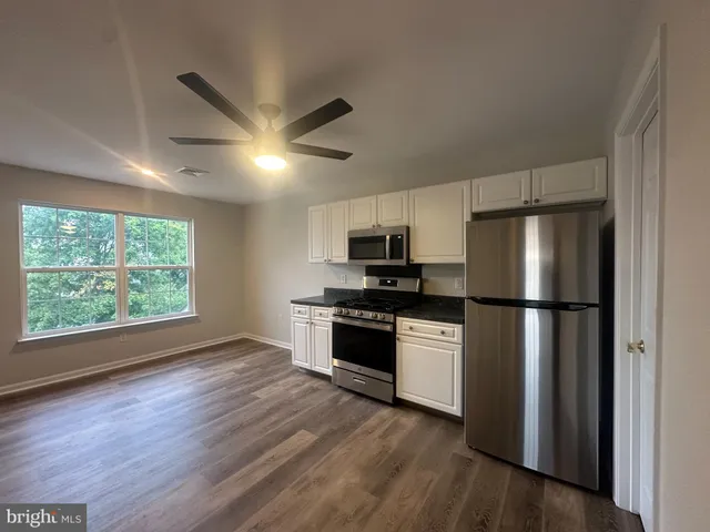 a kitchen with stainless steel appliances a refrigerator a stove a microwave and wooden floors