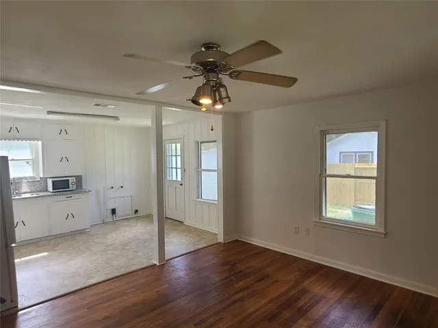 a view of empty room with wooden floor and ceiling fan