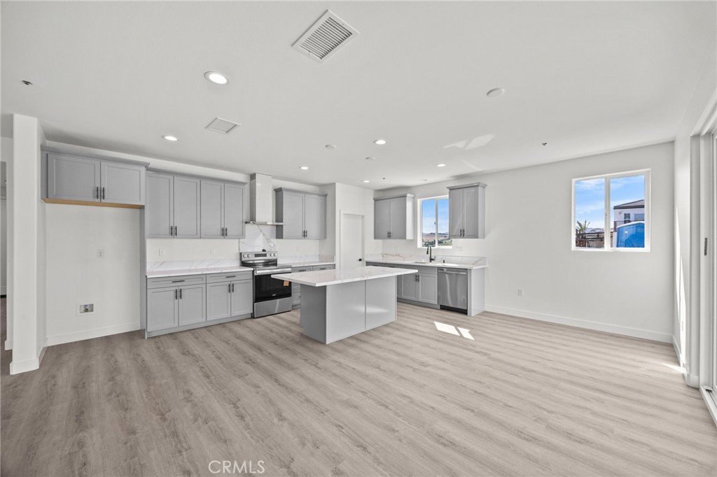 16765 La Bella Villa Riverside, CA 92503 - Photo 5 of 27 a large white kitchen with a center island wooden floor and stainless steel appliances
