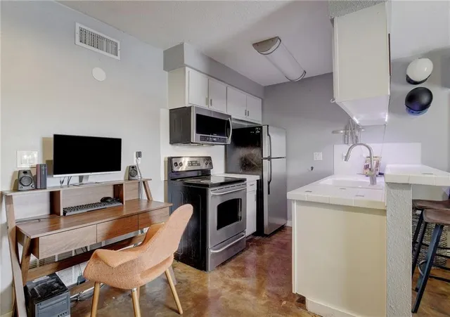 a living room with furniture a flat screen tv and kitchen view