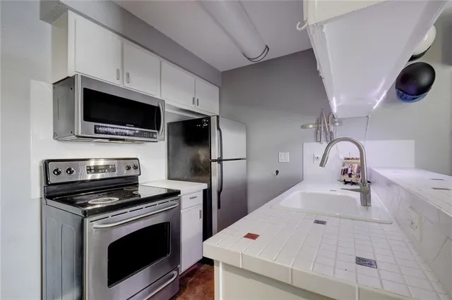 a kitchen with stainless steel appliances a stove microwave and sink