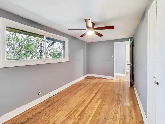 a view of empty room with wooden floor and fan