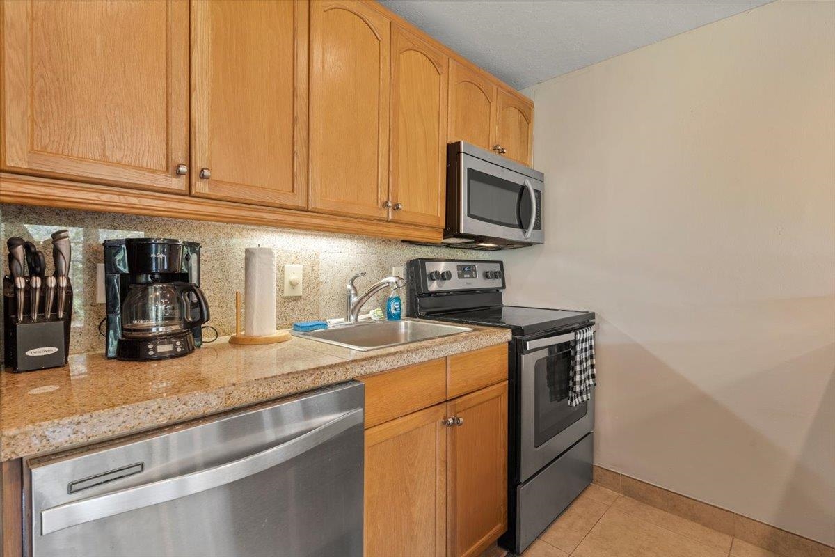 2495 South Kihei Road, Unit 254 Kihei, HI 96753 - Photo 12 of 30 a kitchen with stainless steel appliances granite countertop a sink a stove and microwave with wooden floor