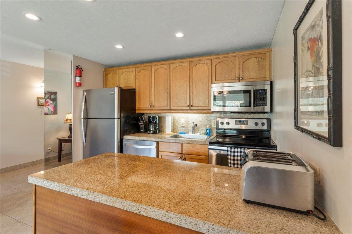 2495 South Kihei Road, Unit 254 Kihei, HI 96753 - Photo 14 of 30 a kitchen with kitchen island a refrigerator stove and microwave