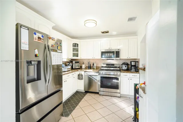 a kitchen with stainless steel appliances granite countertop a refrigerator and a stove top oven
