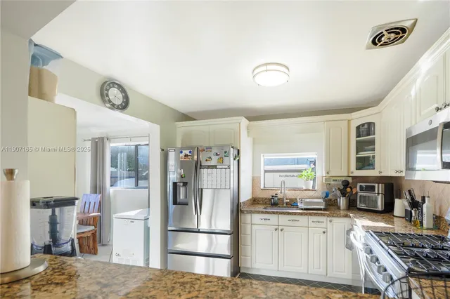 a kitchen with stainless steel appliances granite countertop a refrigerator and a stove top oven