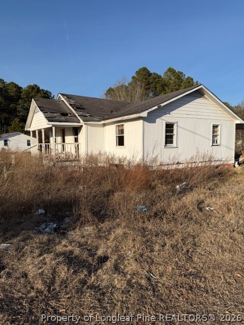 4201 Dudley Road Fayetteville, NC 28312 - Photo 4 of 13 a view of a white house next to a yard with plants and large trees