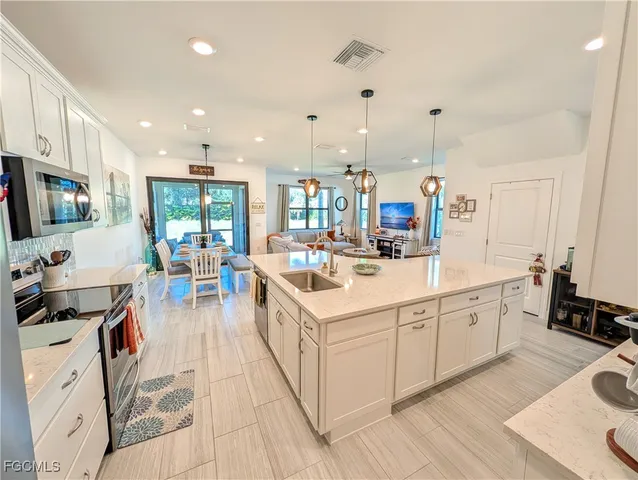 a kitchen with stainless steel appliances kitchen island granite countertop a sink and white cabinets
