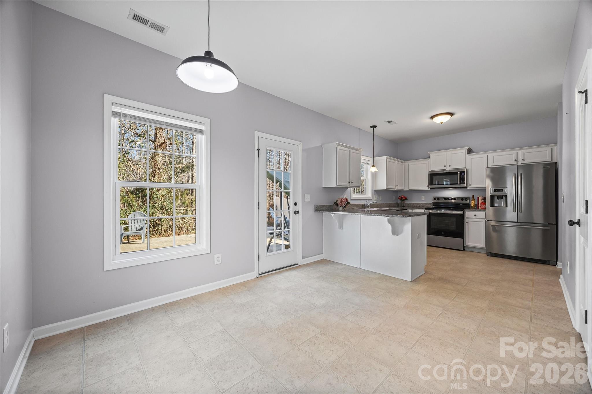 244 Makayla Court Fort Mill, SC 29715 - Photo 5 of 17 a large kitchen with stainless steel appliances granite countertop a stove a sink dishwasher a refrigerator and a dining table with wooden floor