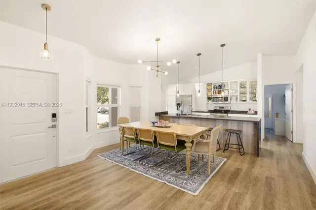 a kitchen with stainless steel appliances granite countertop a refrigerator a oven and white cabinets with wooden floors