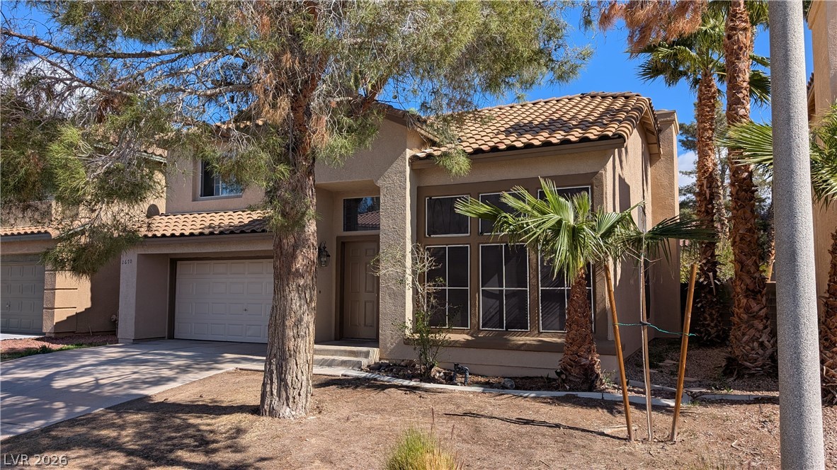 This desert-landscaped home features a classic tile roof and an attached garage.
