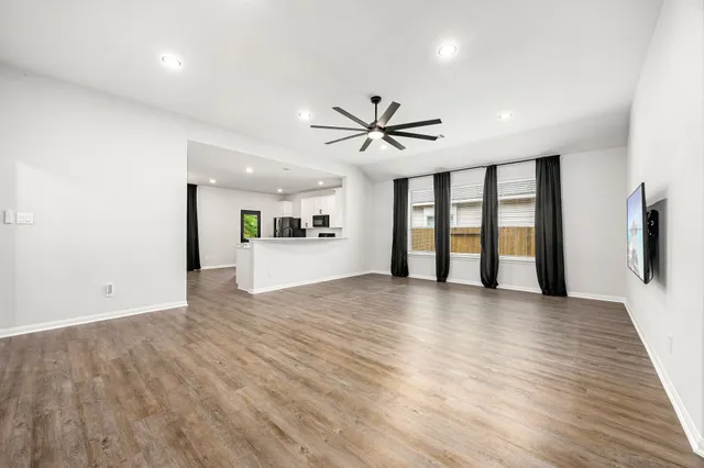 a view of an empty room with a window and a kitchen