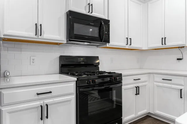 a kitchen with stainless steel appliances granite countertop white cabinets and a stove top oven