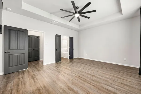 an empty room with wooden floor and ceiling fan