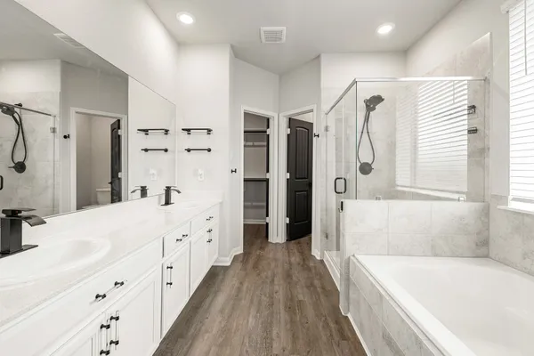 a bathroom with a tub sink shower and two mirror