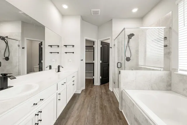 a bathroom with a tub sink shower and two mirror