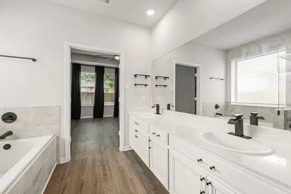 a bathroom with a double vanity sink a mirror and a bathtub