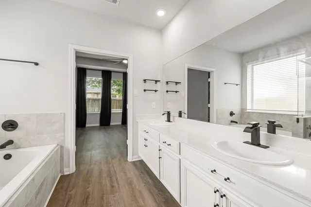 a bathroom with a double vanity sink a mirror and a bathtub