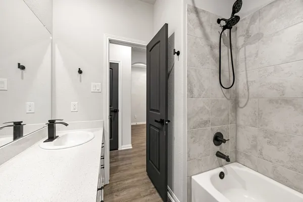 a bathroom with a tub sink vanity and shower