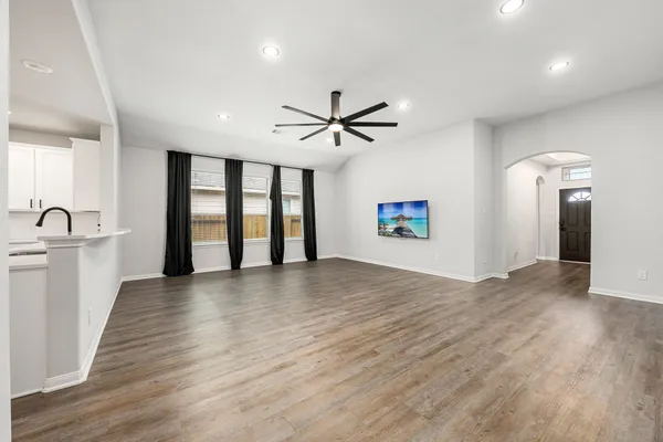 an empty room with wooden floor and a ceiling fan