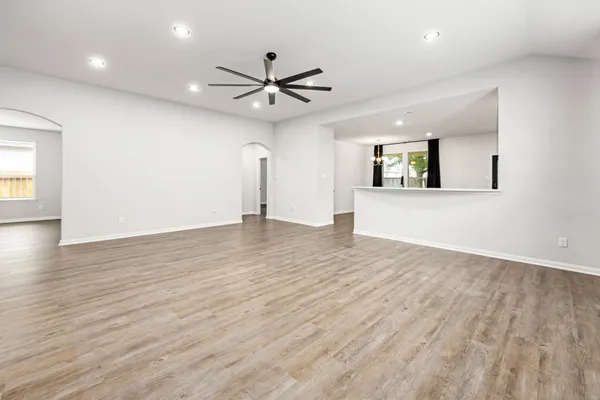an empty room with wooden floor a ceiling fan and windows