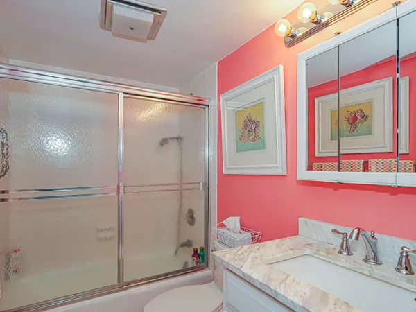 a bathroom with a granite countertop shower sink vanity and mirror