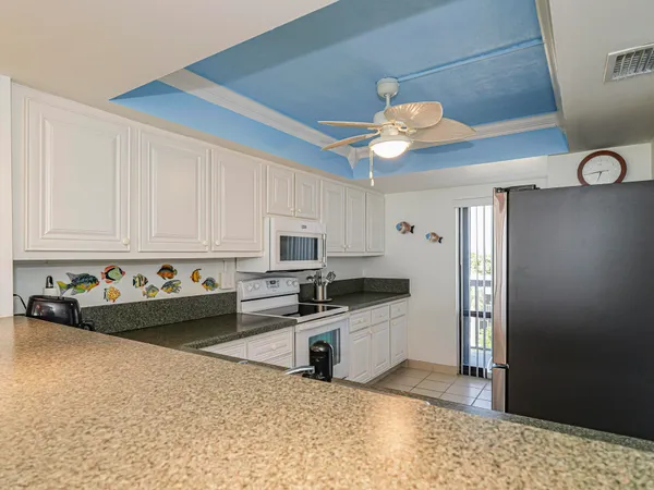 a kitchen with granite countertop a stove a sink and a refrigerator