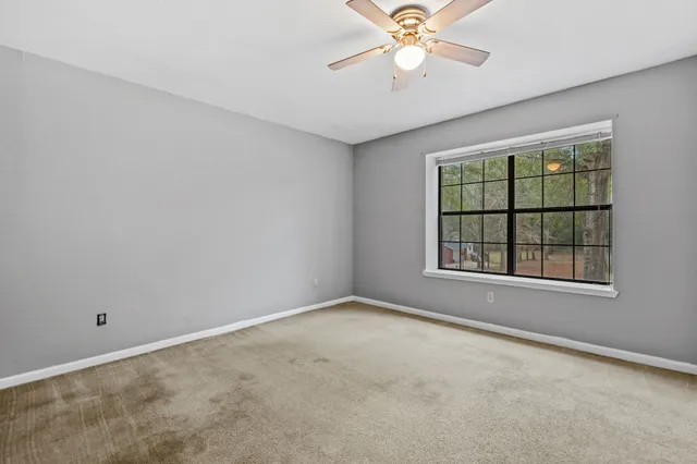 an empty room with windows and chandelier fan