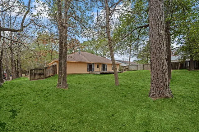 a view of a house with a big yard and large trees