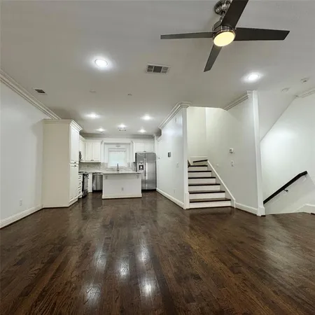 a view of an empty room with a kitchen and wooden floor