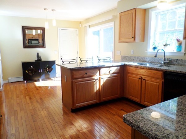 580 R Water Street Framingham, MA 01701 - Photo 5 of 17 a kitchen with stainless steel appliances granite countertop wooden cabinets a sink a stove a dining table and chairs