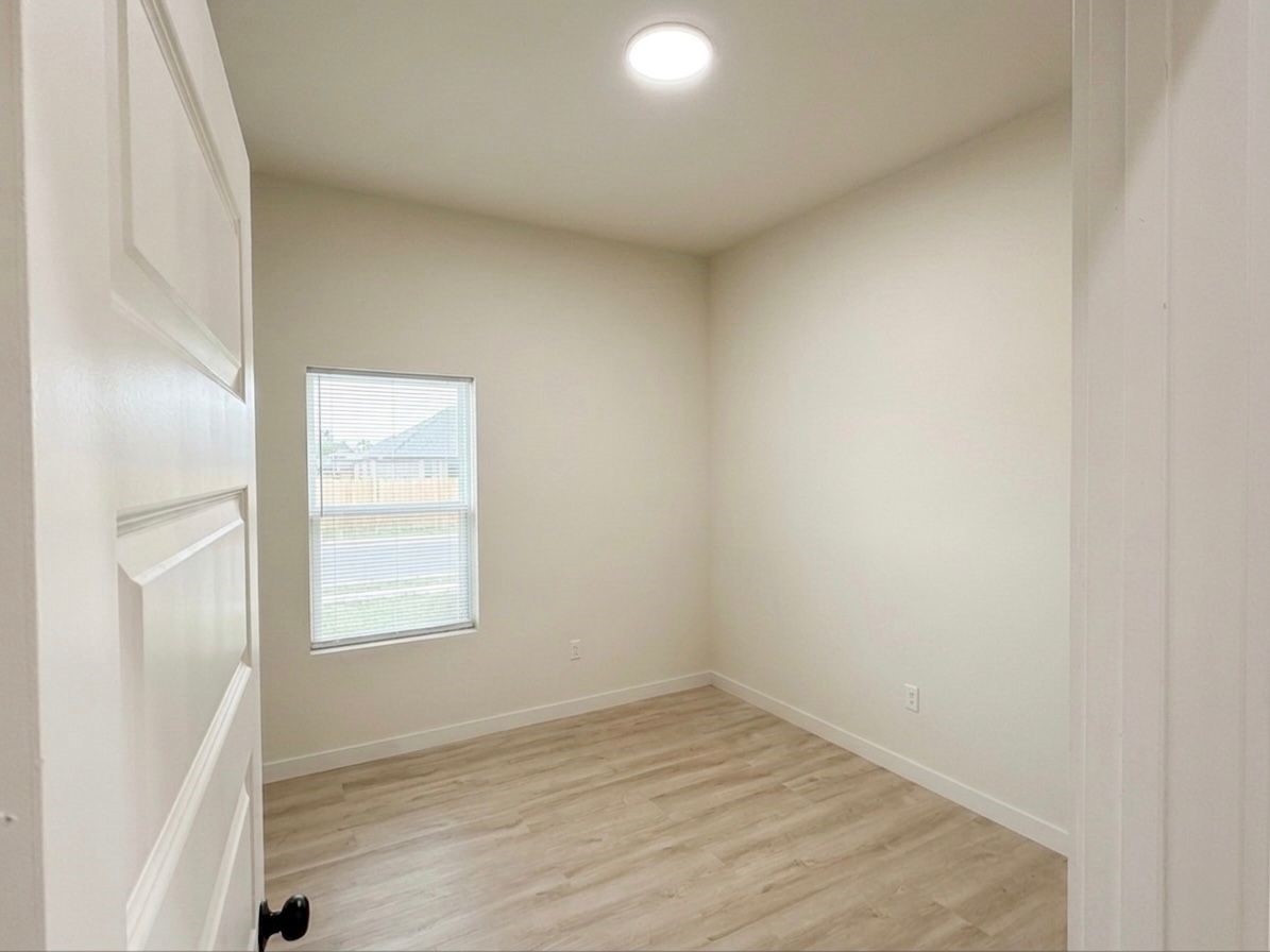 9744 Garcroft Street Houston, TX 77029 - Photo 5 of 17 an empty room with wooden floor and windows