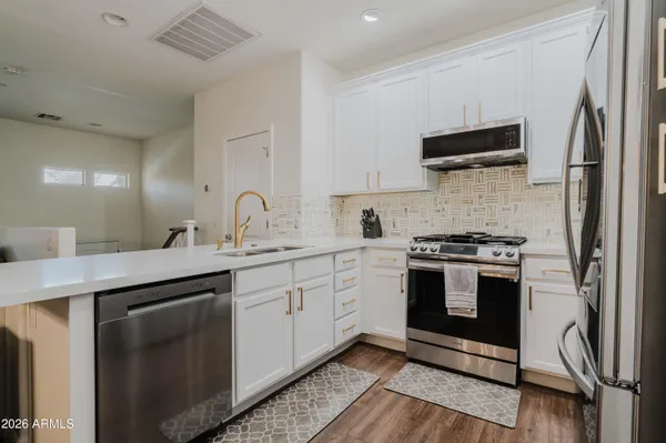 a kitchen with stainless steel appliances white cabinets a sink and a stove