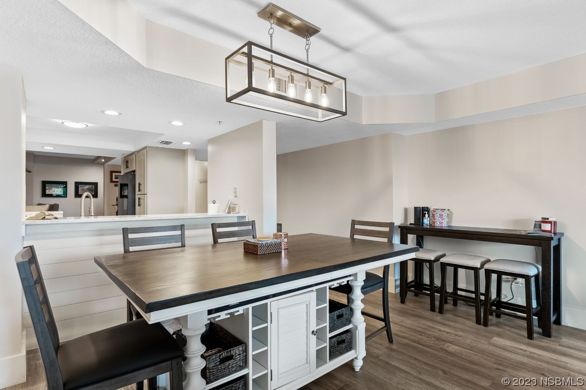 4650 Links Village Drive, Unit A301 Ponce Inlet, FL 32127 - Photo 10 of 54 a kitchen with stainless steel appliances granite countertop a stove a kitchen island a dining table and chairs with wooden floor