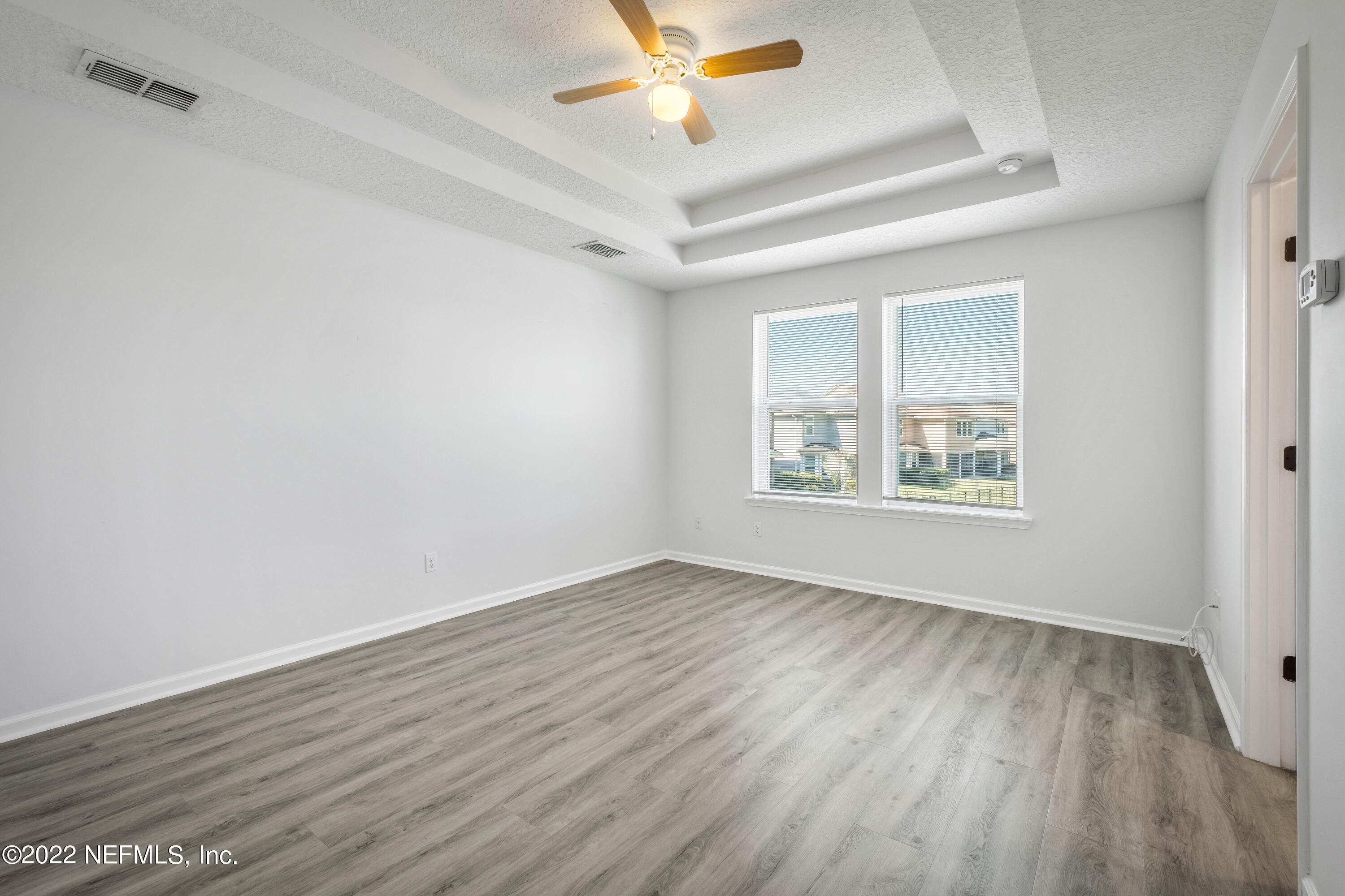 157 Heron Landing Road St. Johns, FL 32259 - Photo 24 of 40 an empty room with wooden floor chandelier fan and windows