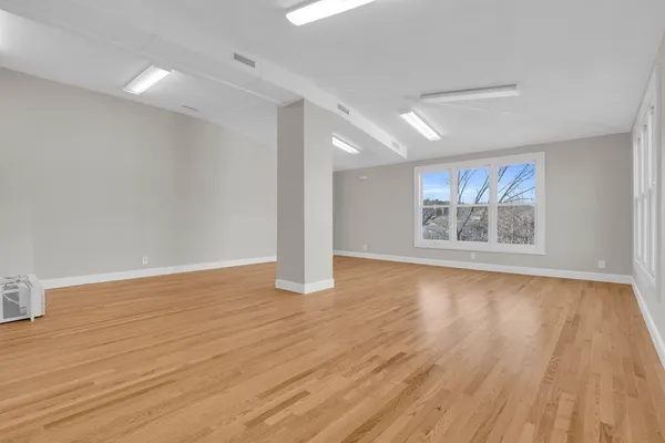 a view of an empty room with wooden floor and a window