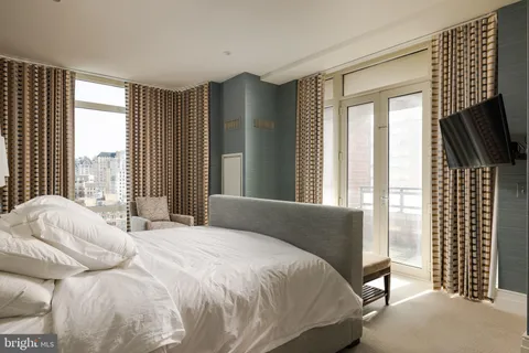 a bedroom with a bed flat screen tv and windows