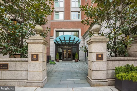 a view of a white house with large windows and a tree