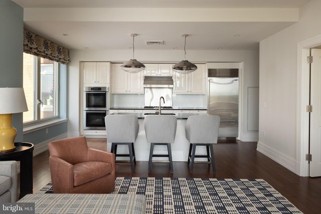 a kitchen with stainless steel appliances kitchen island granite countertop a refrigerator and wooden floor