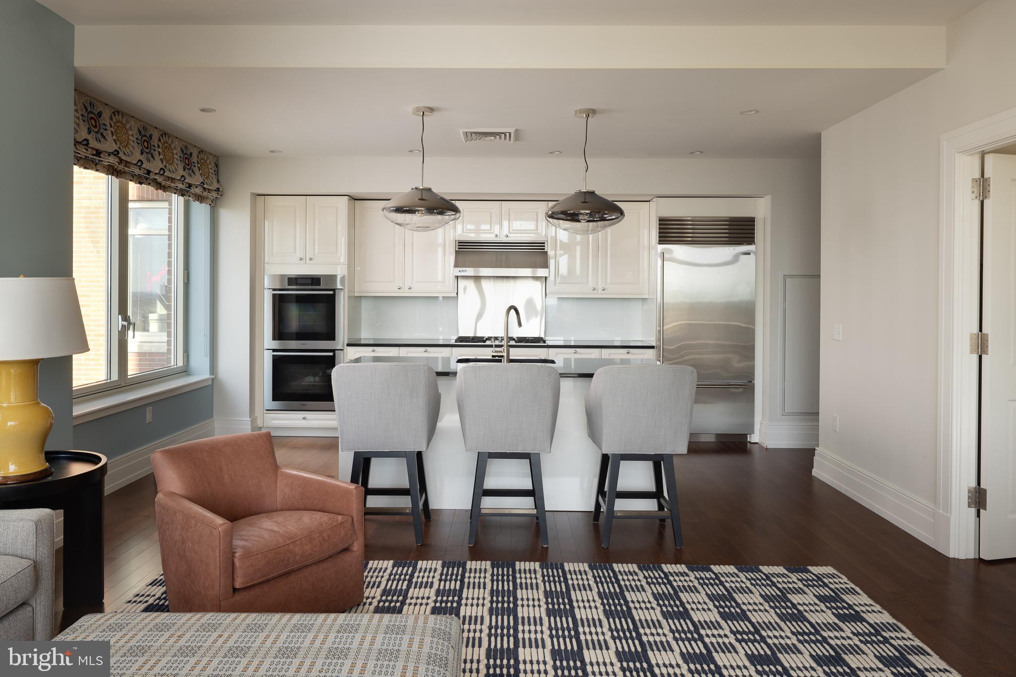 130 South 18th Street, Unit 1804 Philadelphia, PA 19103 - Photo 10 of 36 a kitchen with stainless steel appliances kitchen island granite countertop a refrigerator and wooden floor
