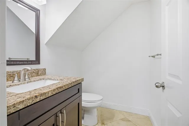 a bathroom with a granite countertop sink a toilet and a mirror
