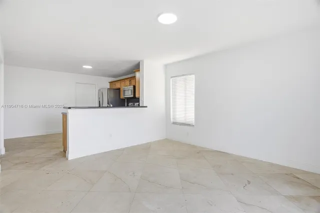 an empty room with windows and refrigerator