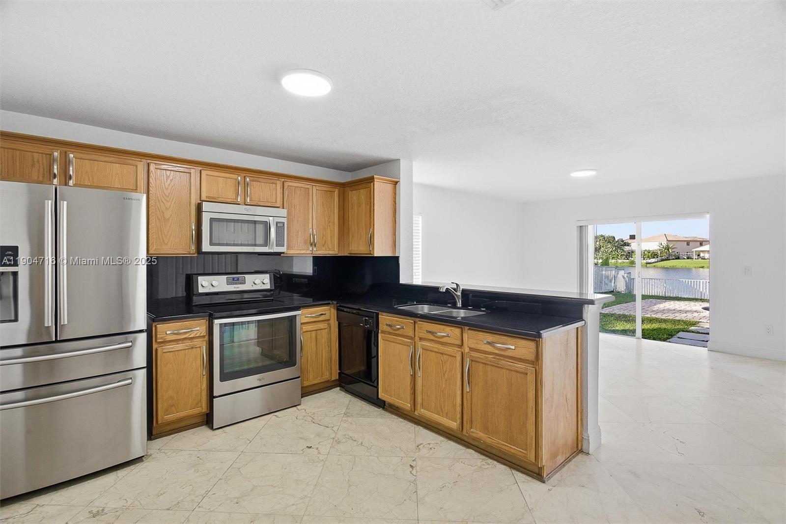 4628 Southwest 125th Lane Miramar, FL 33027 - Photo 14 of 44 a kitchen with stainless steel appliances granite countertop a refrigerator and a sink