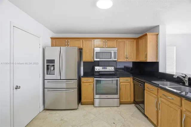 a kitchen with stainless steel appliances granite countertop a refrigerator stove and sink