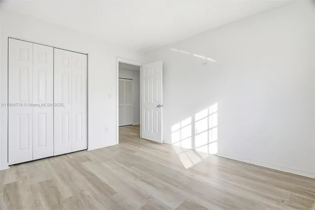 a view of empty room with wooden floor and white walls