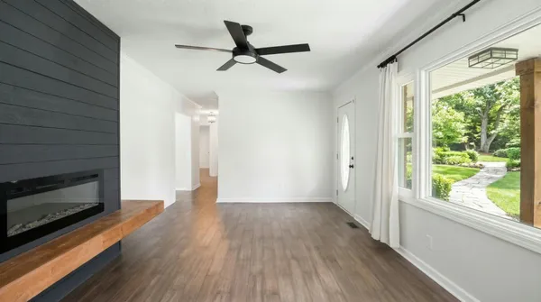 a view of a livingroom with wooden floor a ceiling fan and windows