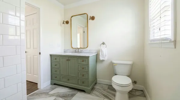 a bathroom with a granite countertop toilet sink and mirror
