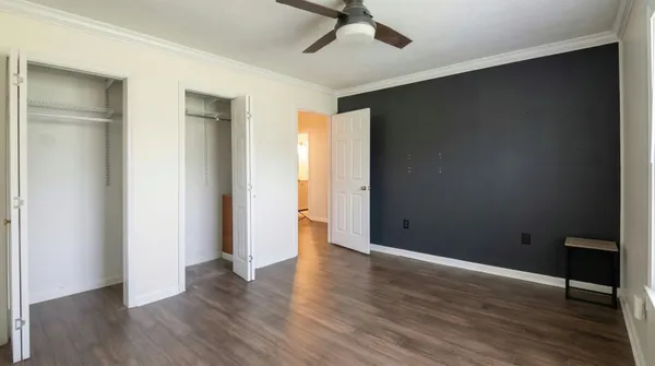 an empty room with wooden floor and a ceiling fan