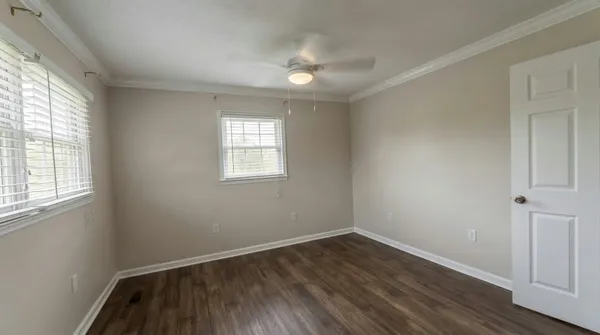 an empty room with wooden floor and windows